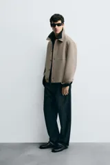 Sobrecamisa color beige de corte cuadrado, con cuello solapa, manga larga con puños abotonados, bolsillos laterales y cierre frontal con botones.