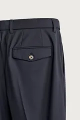 Pantalón de corte regular fit confeccionado en tejido con lana. Presenta cintura ajustable con cinturón integrado, pliegues frontales, bolsillos laterales y bolsillos traseros de doble vivo. Cierre frontal con cremallera y botón.