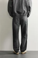 Pantalón de jean corte slim fit con efecto lavado, tiro medio, cinco bolsillos y cierre frontal con cremallera y botón.