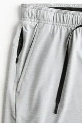 Short deportivo gris claro de tejido funcional con tecnología DryMove™, corte estándar, cintura elástica con cordón de ajuste negro, bolsillos laterales y aberturas en el bajo.