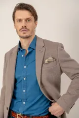Chaquetón de lana color beige, con solapas clásicas, cierre frontal de botones y bolsillo en el pecho con pañuelo decorativo.