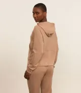 Campera deportiva color beige, con cierre frontal y capucha ajustable con cordón.