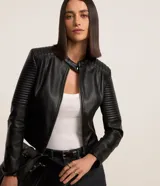 Campera negra de cuero sintético con cuello mao, cierre frontal con cremallera y mangas largas con detalle de pespuntes horizontales.