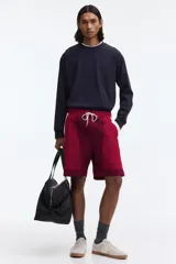 Short deportivo de nylon en bloques de color rojo, bordó y blanco. Cuenta con elástico revestido y cordón de ajuste blanco en la cintura, bolsillos laterales, aberturas cortas en el bajo y suspensor interior de malla.