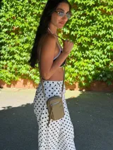 Bandolera compacta color rosado, con correa regulable y desmontable. Tiene apertura superior, bolsillo frontal con cierre y detalle de borla, y bolsillo trasero sin cierre. El interior está forrado en tela y cuenta con un bolsillo adicional.