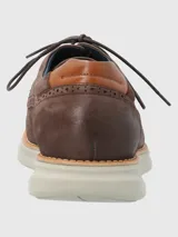 Zapato de estilo casual confeccionado en cuero marrón con detalles de perforaciones decorativas tipo brogue. Cuenta con cierre de cordones, forro interior de cuero y una suela de goma EVA ligera y flexible con tecnología Flex.