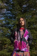 Chaqueta negra con estampado de hojas en tonos rosa, violeta y marrón. Diseño acolchado con cuello clásico y cierre frontal con botones.