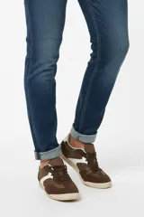 Zapatilla de estilo urbano con diseño de paneles en tonos marrón y blanco, confeccionada en una combinación de gamuza y material textil, con suela de goma plana.