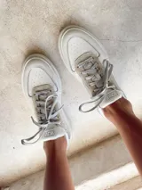 Championes blancos de cuero sintético con detalles en gamuza gris en la puntera y el talón.