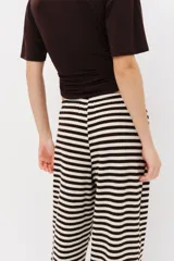 Pantalón de punto suave con patrón de rayas horizontales en color marrón y blanco, tiro medio con cintura elástica, cordón ajustable y piernas amplias de corte recto.