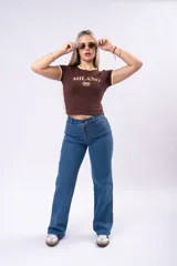 Remera de corte ajustado color marrón con cuello y bordes de mangas en contraste color crema. Presenta un estampado frontal con la palabra 'MILANO' y el número '96' rodeado por una corona de laureles en color crema.