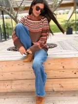 Sweater de punto con diseño jacquard en la parte superior, cuello redondo y mangas largas. Presenta una combinación de colores en tonos tierra, marrón y rosado.