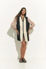 Túnica corta de algodón con cuello clásico y mangas largas. Presenta un diseño de bloques de color en negro, beige y rosa pálido.