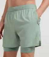 Bermuda deportiva verde militar con short de compresión incorporado, cintura elástica y cordón ajustable, confeccionada en microfibra de poliéster y elastano.