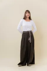 Pantalón wide leg de tiro alto en color negro, con diseño de pinzas delanteras que aportan volumen y caída fluida. Incluye bolsillos laterales y un lazo desmontable en la cintura que combina cordón con cinta de estampado animal print.