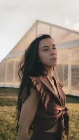 Top de lino color marrón con escote en V, mangas cortas con volados estructurados y lazo frontal ajustable para anudar.