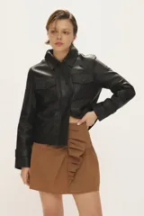 Campera de cuero negro al cuerpo, con cuello camisero, bolsillos de parche con solapa en el pecho y cierre frontal con broches a presión.