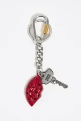 Llavero de metal plateado marca Bimba y Lola con charms colgantes. Incluye un mosquetón con detalle dorado, una cadena de eslabones, un dije en forma de llave con el logo grabado y un dije en forma de labios rojos con incrustaciones de cristales al tono.