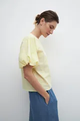 Blusa amarilla con estampado floral, mangas cortas abullonadas y cuello redondo.