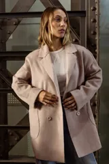 Tapado de paño color rosado, de corte oversized y diseño cruzado. Presenta solapas clásicas, mangas largas con puños vueltos y amplios bolsillos delanteros. Cierre frontal con un botón visible.