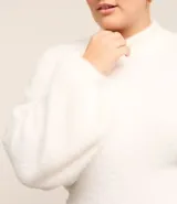 Suéter color beige de punto con textura de pelitos, cuello alto y mangas largas.