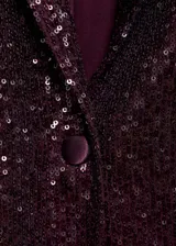Chaqueta de corte recto con diseño de lentejuelas en color bordó, cuello con solapa, cierre frontal de un botón, manga larga y dos bolsillos delanteros con solapa.