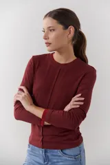 Remera color borgoña con cuello redondo y mangas largas. Presenta un corte recto y detalles a contratono en puños y cuello.