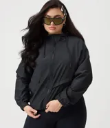 Campera rompevientos deportiva negra con capucha, cierre frontal, bolsillos funcionales y puños y ruedo con elástico.