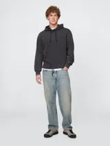 Buzo con capucha de corte holgado, color gris oscuro con efecto lavado, mangas largas con puños acanalados y cordón ajustable en el ruedo.