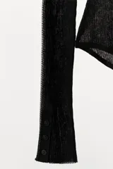 Body semitransparente color negro confeccionado en tejido de punto fino, de manga larga, con escote redondo y cierre frontal con botones.