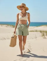 Short color crema con finas rayas verticales grises, pretina elastizada con cordón de ajuste, bolsillos delanteros y traseros.