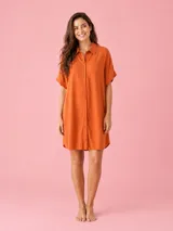 Vestido camisero corto color naranja, confeccionado en viscosa suave y liviana, con cierre frontal de botones, cuello camisero, mangas cortas y detalle de pequeño corazón bordado en el pecho.