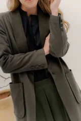 Tapado largo de corte recto y estilo minimalista, confeccionado en tela de color negro. Presenta solapas amplias, bolsillos frontales de parche y un diseño abierto que permite superponer capas.