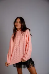 Sweater de punto trenzado color crema, con cuello alto y mangas largas.