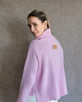 Sweater color crudo de cuello alto con mangas largas y corte holgado.