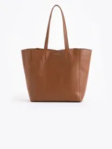 Cartera tipo shopper de cuero vacuno flor graneado, con formato amplio y estructura flexible. Presenta dos cierres verticales decorativos en el frente con tiracierres personalizados y doble manija de hombro.