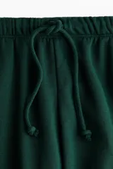 Pantalón tipo jogger de corte holgado y piernas amplias, confeccionado en felpa con interior cepillado. Presenta cintura elástica con cordón de ajuste y bolsillos laterales discretos.