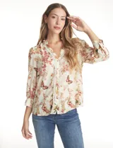 Blusa de gasa con estampado floral y de mariposas, color beige. Presenta cuello a la base fruncido, escote en V con aplique de puntilla vertical en la parte delantera y cierre central con botones forrados. Posee mangas tres cuartos con puños abotonados.