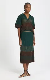 Camisa de punto calado con rayas horizontales en verde oscuro y marrón, cuello polo en V, mangas cortas holgadas y ribetes acanalados en los puños y el bajo.