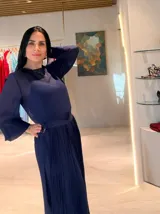 Vestido midi de color azul marino, con mangas largas ligeramente abullonadas y falda plisada. Presenta un diseño con cintura definida y un detalle de hebilla lateral.