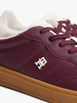 Zapatillas de corte bajo confeccionadas en piel napa brillante color bordó, con suela de goma color caramelo. Presentan insignia metálica del monograma TH en el lateral y detalle en blanco en el talón.