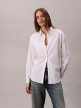 Camisa blanca de algodón con cuello camisero, manga larga y cierre frontal con botones. Presenta un sutil estampado integral de logo de Calvin Klein.