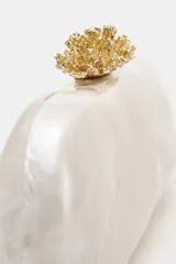 Bolso de mano tipo clutch con acabado nacarado y cierre de clip con detalle metálico dorado en la parte superior. Incluye cadena metálica para usar como bandolera.