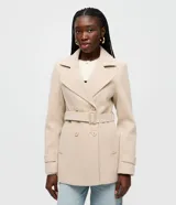 Saco de paño color beige, de doble botonadura, con solapas amplias, bolsillos laterales y cinturón ajustable con hebilla del mismo material.