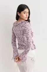 Top blanco de encaje con escote en V, volados y mangas largas con lazos.