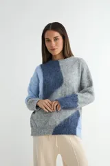 Buzo de tejido de punto con diseño de bloques de color en tonos blanco y gris, de cuello redondo y manga larga.