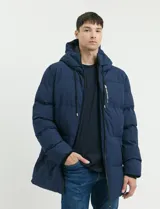 Campera puffer de corte largo, color verde militar, con capucha fija, cierre frontal y puños elásticos internos.