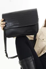 Cartera bandolera de cuero vacuno color bordó, con solapa frontal de textura símil cocodrilo y detalles de costuras pespunteadas en blanco. Cuenta con correa ajustable y cierre superior.