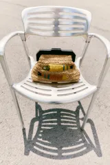 Bolso de mano tipo clutch confeccionado en rafia color beige con asa de madera oscura y cierre a presión. Decorado con dos peces bordados con cuentas y rafia de colores amarillo, marrón y verde.