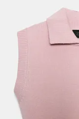 Chaleco de punto color blanco, estilo polo, sin mangas (manga sisa) y cuello solapa. La parte inferior termina en rib.